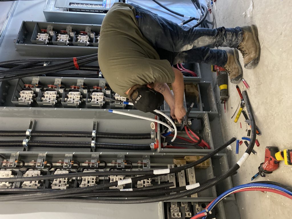 Électricien au travail sur un tableau de distribution électrique d'un immeuble à logements
