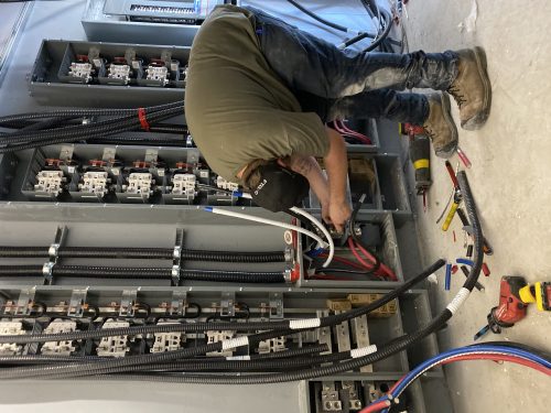 Électricien au travail sur un tableau de distribution électrique d'un immeuble à logements