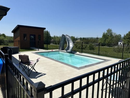 Piscine résidentielle avec glissade et pool house au fond de la cour clôturée