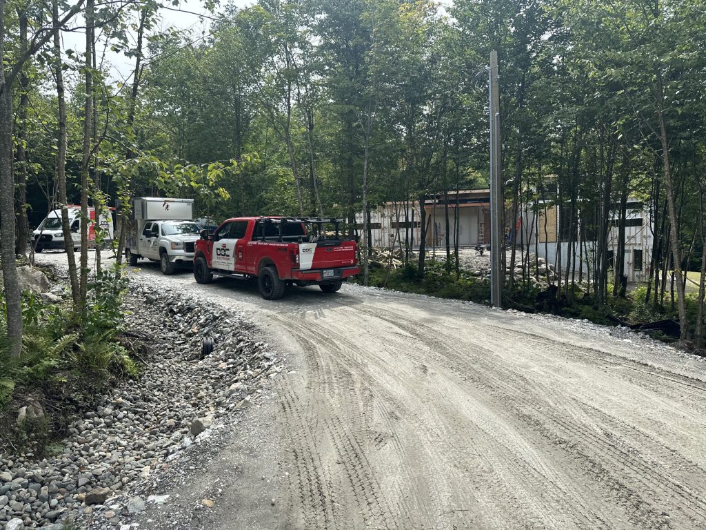 Camions de service Doc Électrique sur un chemin de gravier près d'un chantier résidentiel