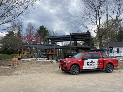 Chantier résidentiel avec structure d'acier apparente et camion de service Doc Électrique