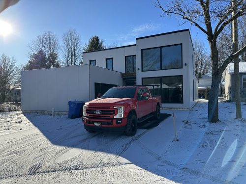 Résidence moderne neuve en hiver avec camion de service Doc Électrique dans l'entrée
