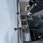 Technicien inspectant le câblage électrique d'une unité de toiture avec caméra thermique