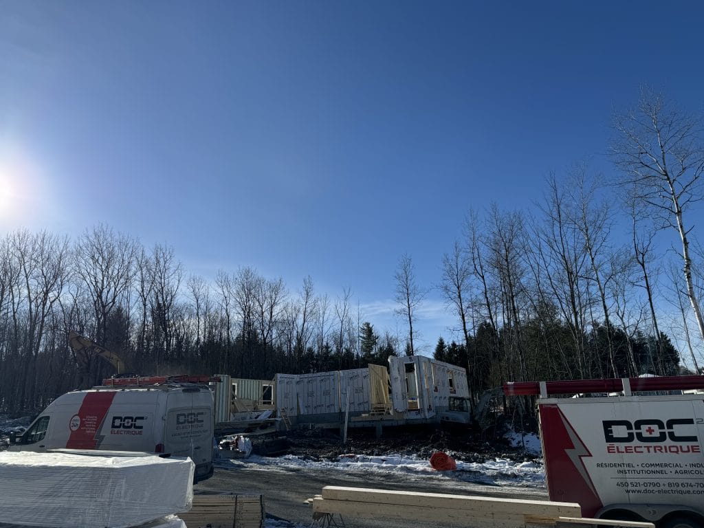 Deux fourgons Doc Électrique sur un chantier de construction d'unités en rangée, en hiver