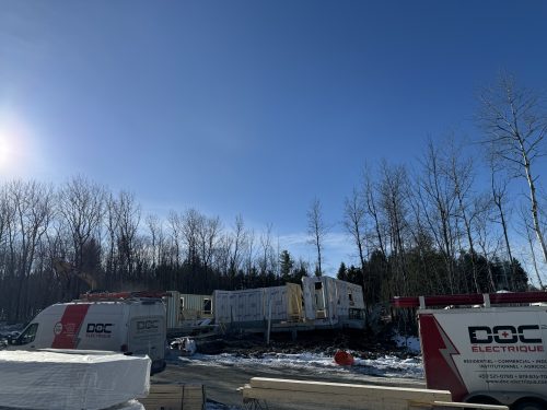 Deux fourgons Doc Électrique sur un chantier de construction d'unités en rangée, en hiver