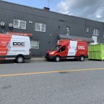 Véhicules Doc Électrique stationnés devant un bâtiment industriel