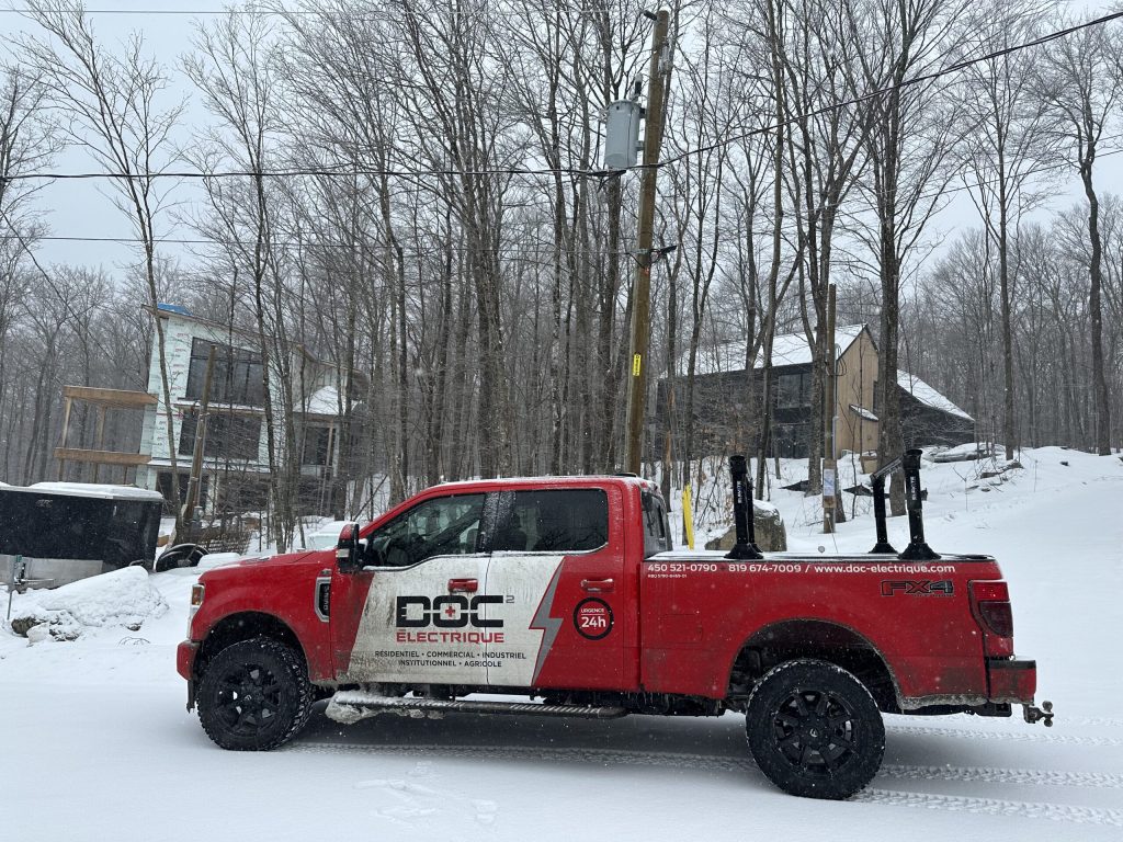 Camion Doc Électrique près d'un poteau avec compteur électrique, chantiers résidentiels en forêt
