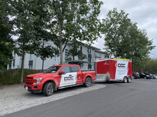 Camion et remorque Doc Électrique stationnés devant un immeuble à logements
