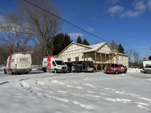 Bâtiment commercial en construction avec plusieurs véhicules Doc Électrique, en hiver