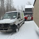Véhicules de service Kohler et Doc Électrique stationnés près d'une résidence, en hiver