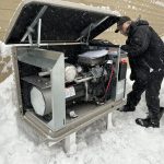 Technicien inspectant le moteur d'une génératrice Kohler résidentielle, en hiver