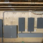 Plusieurs panneaux électriques et disjoncteur principal installés dans un sous-sol
