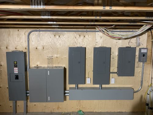 Plusieurs panneaux électriques et disjoncteur principal installés dans un sous-sol