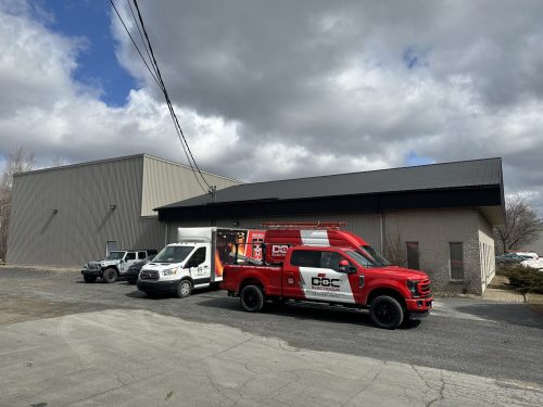 Véhicules de service Doc Électrique stationnés devant un bâtiment industriel