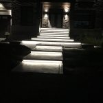 Escalier extérieur illuminé par bandeau DEL intégré devant une entrée en pierre, la nuit