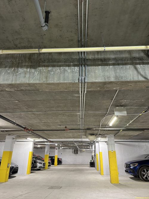 Conduits électriques installés au plafond d'un garage souterrain d'immeuble à logements