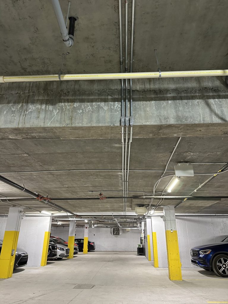 Conduits électriques installés au plafond d'un garage souterrain d'immeuble à logements