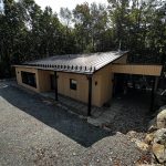 Chalet moderne à toit métallique avec appliques d'éclairage extérieur près des entrées