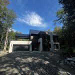 Résidence contemporaine en pierre et bois noir avec appliques d'éclairage extérieur