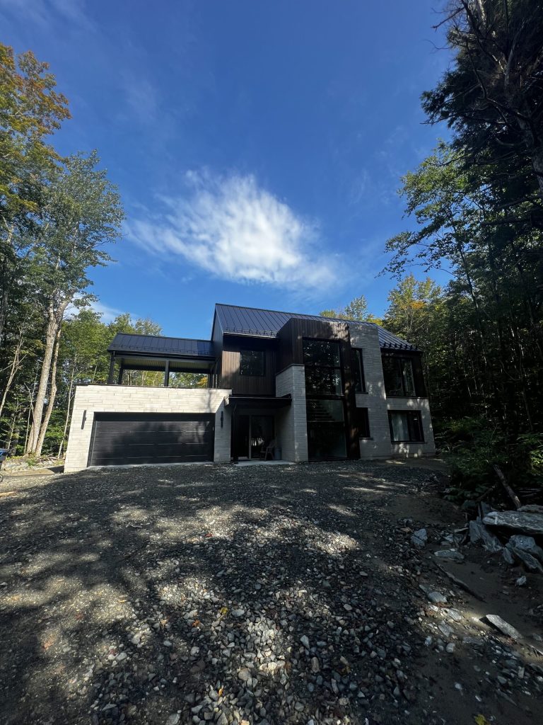 Résidence contemporaine en pierre et bois noir avec appliques d'éclairage extérieur