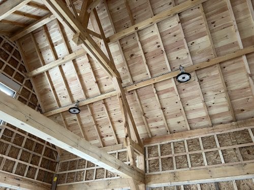 Luminaires industriels installés sur charpente de bois d'un bâtiment agroalimentaire