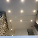 Plafond cathédrale résidentiel avec multiples spots encastrés au-dessus d'un mur de pierre