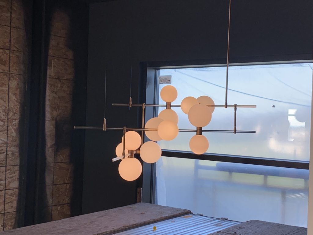 Luminaire suspendu design à multiples globes, en cours d'installation près d'une fenêtre