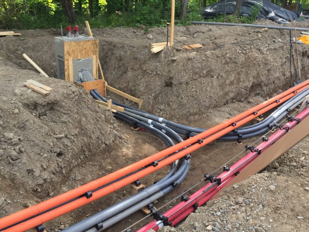 Conduits électriques raccordés à un puits d'accès en béton dans une tranchée