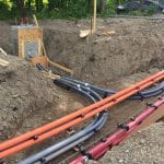 Conduits électriques raccordés à un puits d'accès en béton dans une tranchée