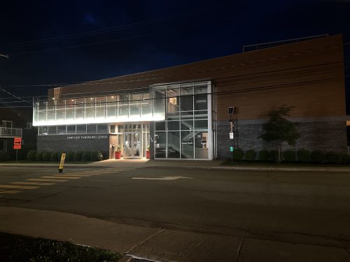 Complexe funéraire avec auvent vitré illuminé, façade éclairée le soir