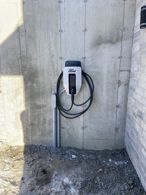 Borne de recharge Ford montée sur un mur de fondation extérieur résidentiel