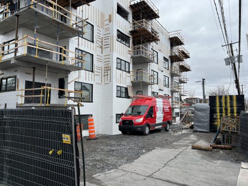 Fourgon Doc Électrique stationné sur un chantier d'immeuble à logements en structure