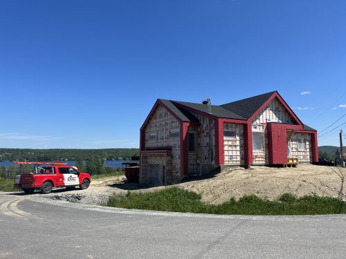 Résidence en construction au bord d'un lac avec camion de service Doc Électrique