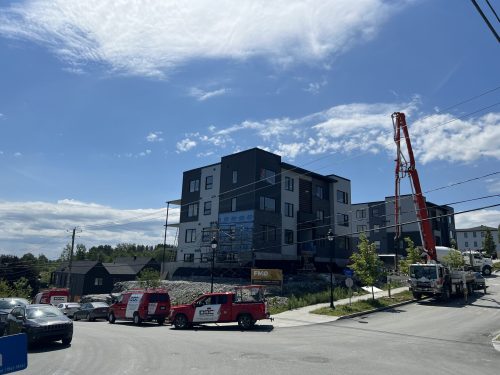 Immeuble à logements en finition avec pompe à béton et véhicules Doc Électrique