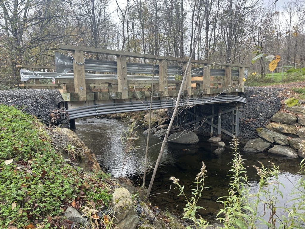 Conduits électriques installés sous un pont en bois traversant un ruisseau