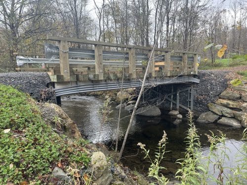 Conduits électriques installés sous un pont en bois traversant un ruisseau