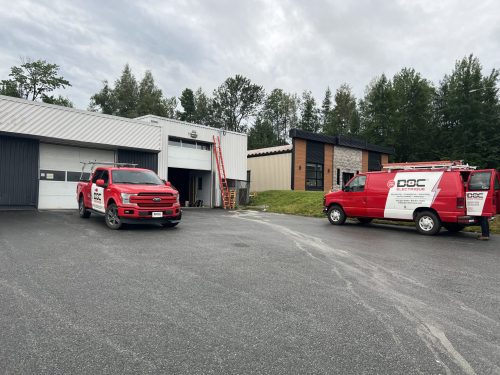 Bâtiment commercial avec portes de garage et véhicules de service Doc Électrique
