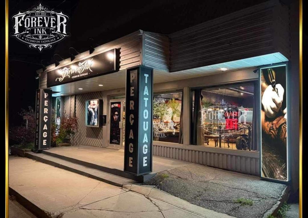 Façade commerciale d'un studio de tatouage illuminée le soir avec enseignes lumineuses