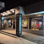 Façade commerciale d'un studio de tatouage illuminée le soir avec enseignes lumineuses