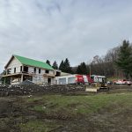Résidence en construction avec toiture en papier vert et véhicules Doc Électrique