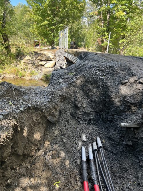 Conduits électriques installés sous une structure de pont près d'un cours d'eau