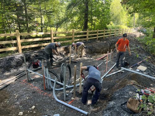 Électriciens installant des conduits dans une tranchée en milieu forestier