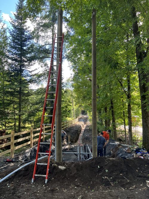 Poteaux électriques neufs et tranchée en cours de raccordement en forêt