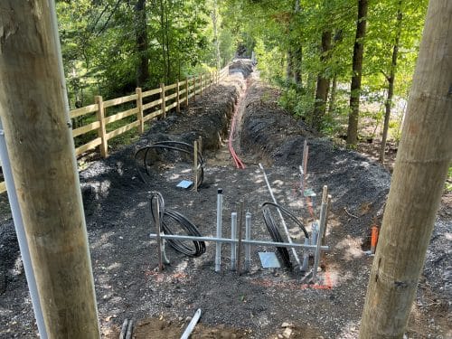 Tranchée avec conduits électriques en cours d'installation en milieu forestier