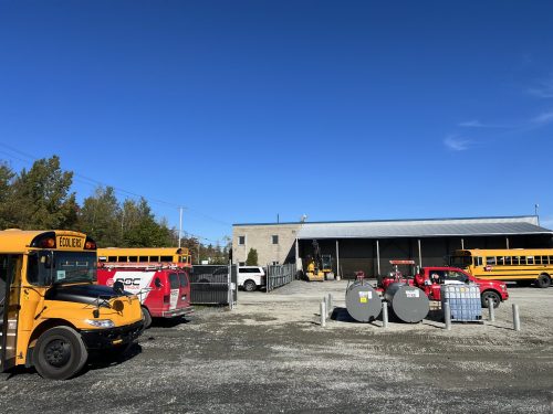 Garage de transport scolaire avec autobus jaunes et fourgon Doc Électrique