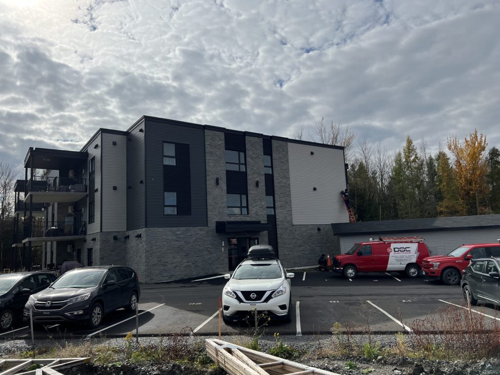 Immeuble à logements avec électricien sur échelle et véhicules Doc Électrique