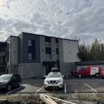 Immeuble à logements avec électricien sur échelle et véhicules Doc Électrique