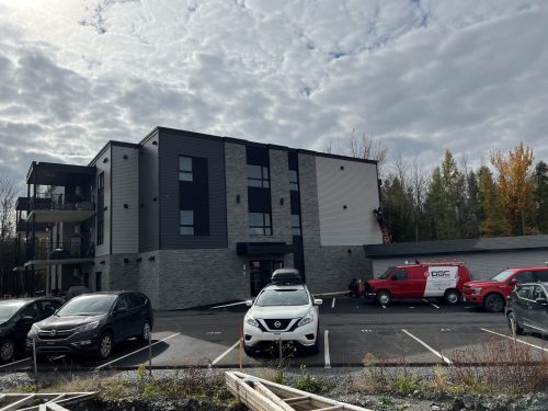Immeuble à logements avec électricien sur échelle et véhicules Doc Électrique