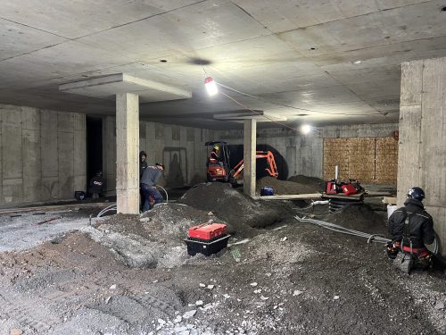 Électriciens au travail dans un garage souterrain en construction d'un immeuble à logements