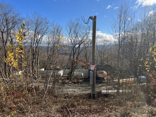 Poteau avec compteur et coffret électrique installés sur un chantier résidentiel en déboisement